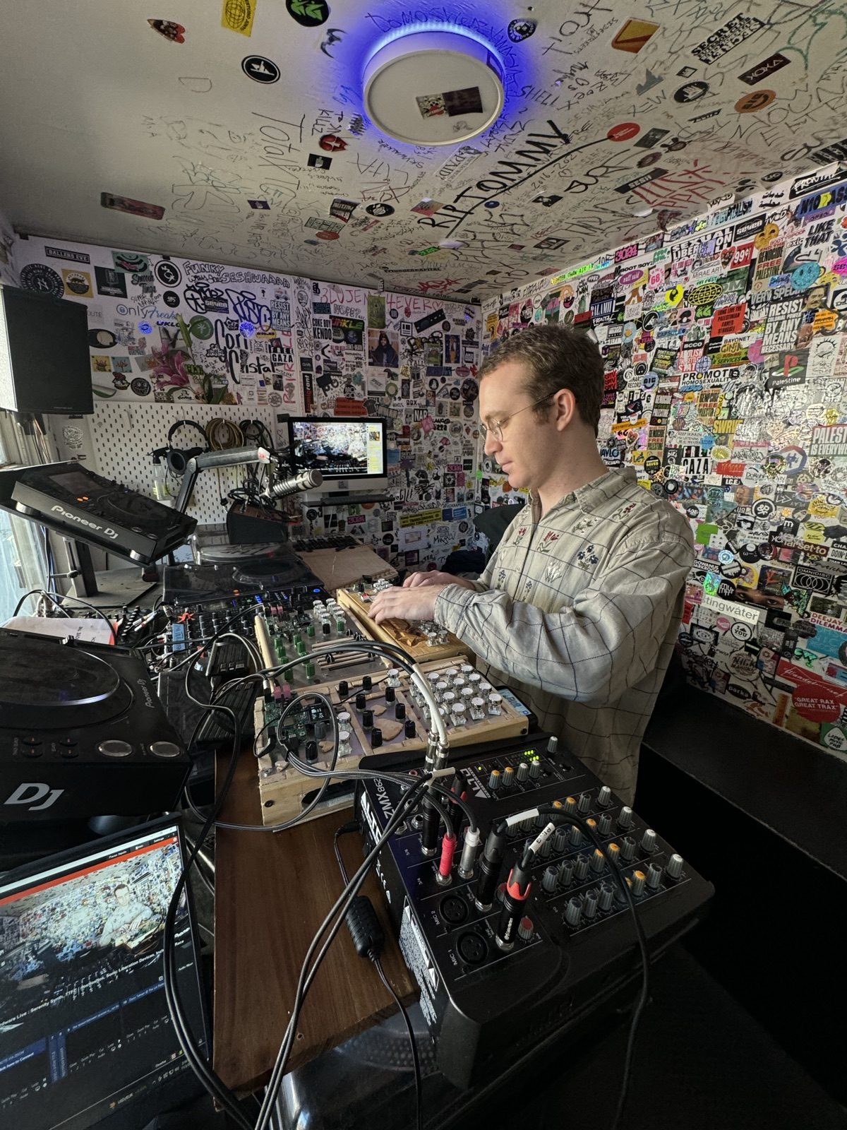 Playing homemade instruments in a sticker-covered radio booth