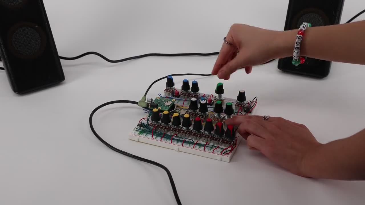Hands patching the breadboard prototype between studio monitors